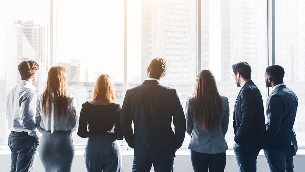Business-Team blickt aus Fenster auf Stadt, Symbol für Digitalisierung.